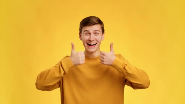 Man Gesturing Thumbs Up With Both Hands Over Yellow Background - Video