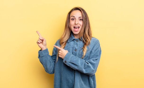 pretty caucasian woman feeling joyful and surprised, smiling with a shocked expression and pointing to the side - Photo, Image