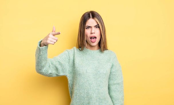 pretty caucasian woman pointing at camera with an angry aggressive expression looking like a furious, crazy boss - 写真・画像