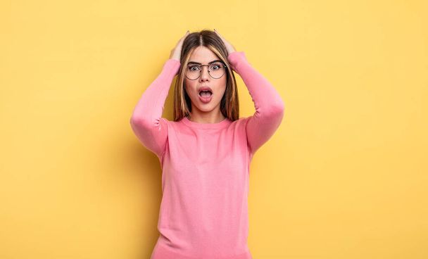 pretty caucasian woman looking unpleasantly shocked, scared or worried, mouth wide open and covering both ears with hands - 写真・画像