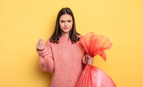 pretty woman making capice or money gesture, telling you to pay. trash bag concept - Photo, image