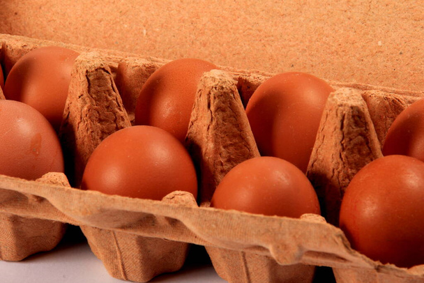 Œufs bruns crus dans une boîte à œufs. gros plan des œufs de poulet dans la boîte à œufs - Photo, image
