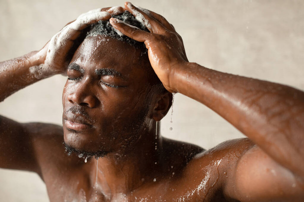 African Guy Washing Head With Eyes Closed Taking Shower Indoor - Foto, immagini