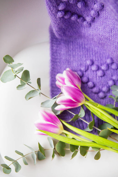 Frühling schöner Strauß lila Tulpen mit Eukalyptus auf einem weißen Stuhl zusammen mit einem lila Pullover. Frühlingsstimmung, 8. März. Postkarte für den Urlaub - Foto, Bild