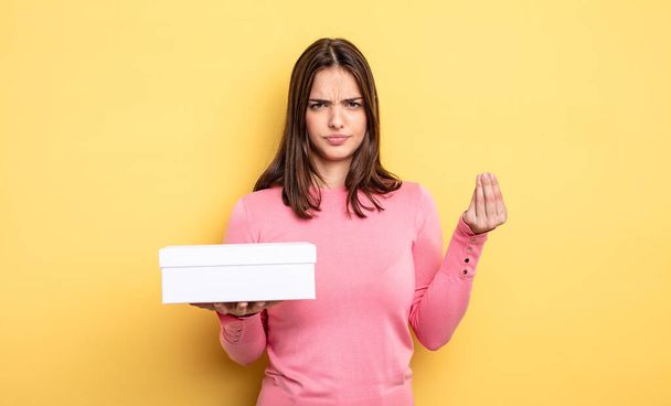 pretty woman making capice or money gesture, telling you to pay. white box packaging concept - Foto, Bild
