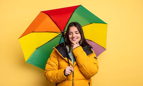 pretty woman smiling with a happy, confident expression with hand on chin. winter and umbrella concept - Photo, Image