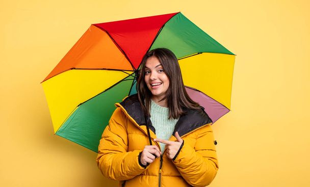 pretty woman smiling cheerfully, feeling happy and pointing to the side. winter and umbrella concept - Φωτογραφία, εικόνα
