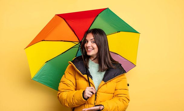 pretty woman smiling cheerfully, feeling happy and showing a concept. winter and umbrella concept - Fotó, kép