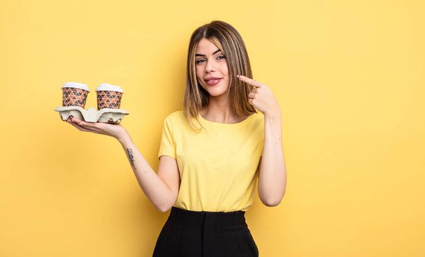 pretty woman smiling confidently pointing to own broad smile. take away coffees concept - Foto, imagen