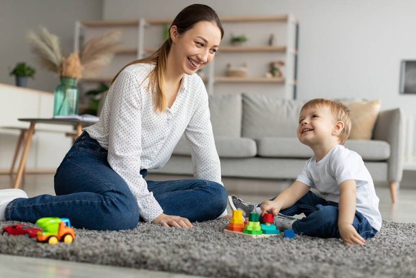 Happy mom playing with toddler son stacking and sorting wooden toy, spending time with kid at home - Fotoğraf, Görsel