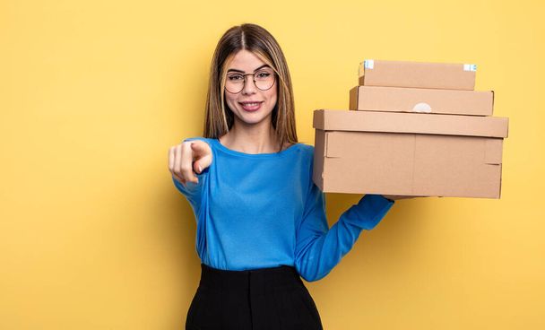 pretty woman pointing at camera choosing you packages boxes concept - Фото, изображение