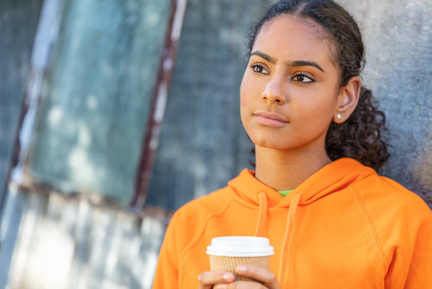 Beautiful mixed race African American girl teenager female young woman looking sad depressed or thoughtful outside with a cup of takeout coffee - Fotografie, Obrázek