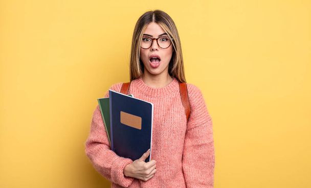 pretty student woman looking very shocked or surprised. books and backpack - Foto, afbeelding