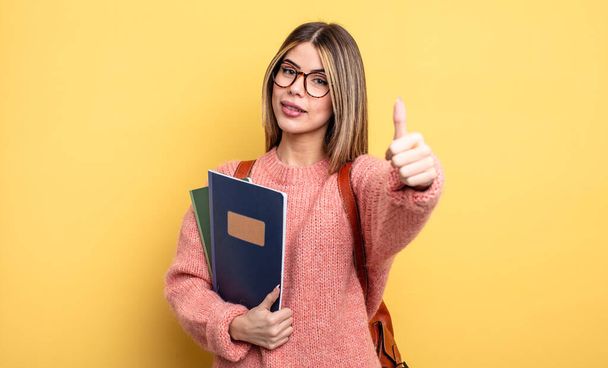 pretty student woman feeling proud,smiling positively with thumbs up. books and backpack - Foto, Bild