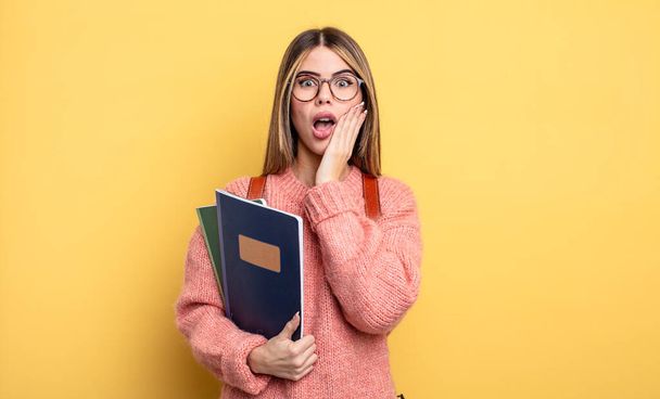 pretty student woman feeling shocked and scared. books and backpack - Foto, afbeelding