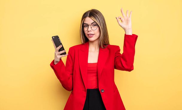 businesswoman feeling happy, showing approval with okay gesture. smartphone concept - Fotó, kép