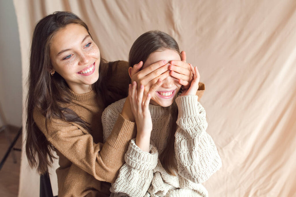 sisters hugging on beige color textile background - Valokuva, kuva