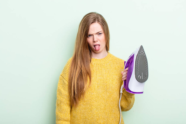 redhair woman feeling disgusted and irritated and tongue out. iron clothes concept - 写真・画像