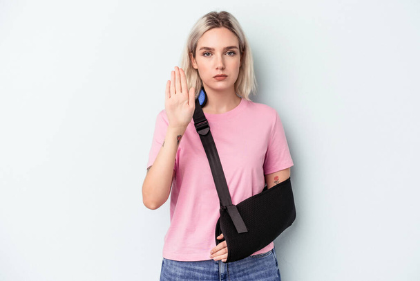 Young caucasian woman with broken hand isolated on blue background standing with outstretched hand showing stop sign, preventing you. - Фото, изображение