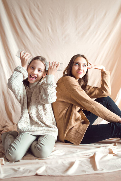 sisters having fun on beige color textile background - Foto, immagini