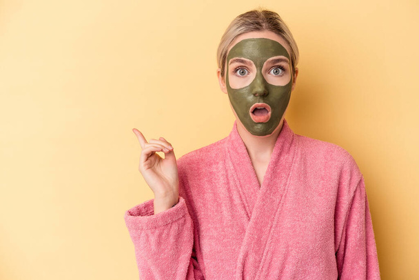 Young caucasian woman wearing face mask isolated on yellow background pointing to the side - Photo, Image