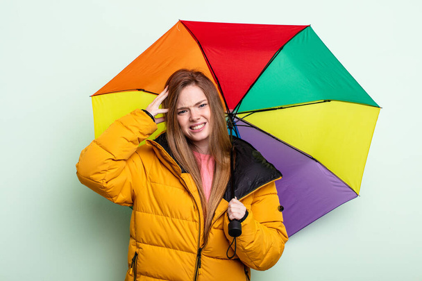 redhair woman feeling stressed, anxious or scared, with hands on head. umbrella concept - Foto, Imagem