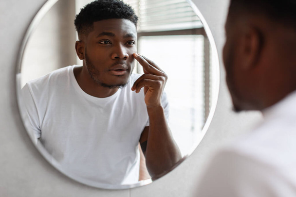 Black Man Touching Face Caring For Under-Eye Skin In Bathroom - Foto, afbeelding