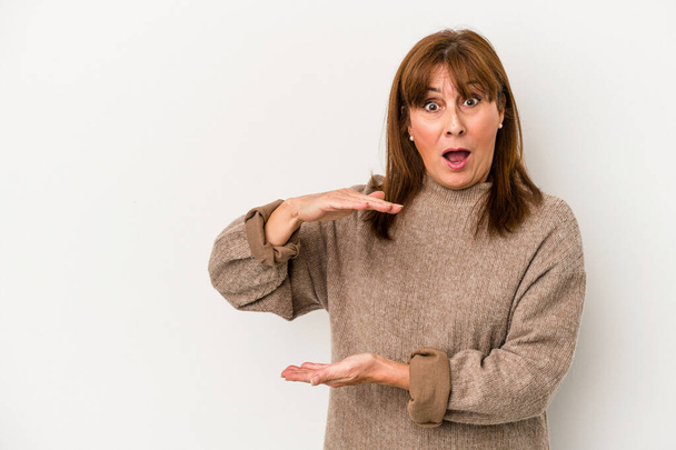 Middle age caucasian woman isolated on white background shocked and amazed holding a copy space between hands. - Photo, Image