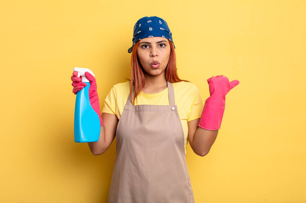 hispanic woman looking astonished in disbelief. cleaning and housekeeper concept - Fotoğraf, Görsel