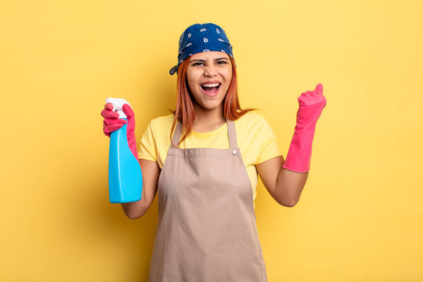 hispanic woman shouting aggressively with an angry expression. cleaning and housekeeper concept - Zdjęcie, obraz