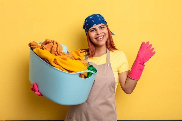 housekeeper smiling happily, waving hand, welcoming and greeting you. washing clothes concept - Foto, Imagem