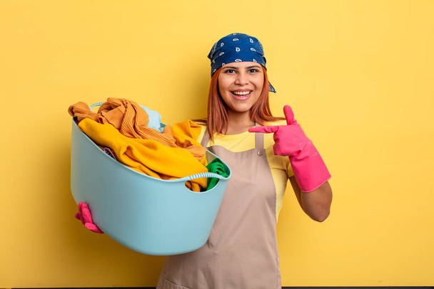 housekeeper looking excited and surprised pointing to the side. washing clothes concept - Foto, afbeelding