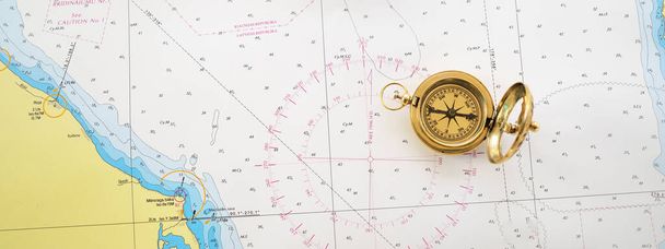Retro stijl gouden kompas (zonnewijzer) en oude witte nautische kaart close-up. Vintage stilleven. Zeilaccessoires. Reizen en navigatie thema - Foto, afbeelding
