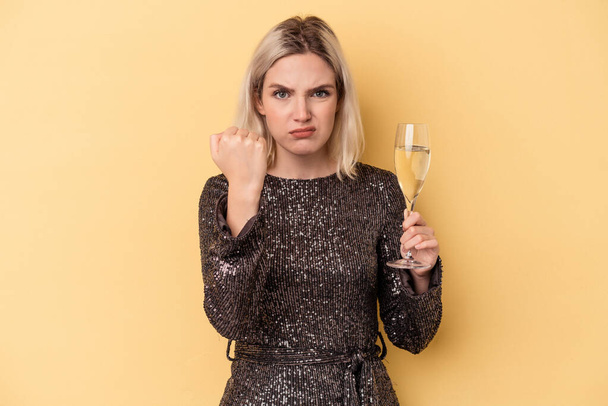 Young caucasian woman celebrating new year isolated on yellow background showing fist to camera, aggressive facial expression. - Fotografie, Obrázek