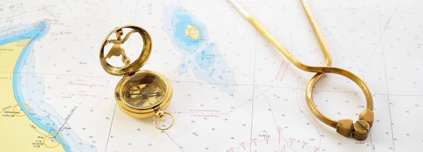 レトロスタイルの黄金のコンパス(日時計) 、アンティークヴィンテージのW&HC 6 "真鍮製の仕切りキャリパー航海ナビゲーションチャートツールと古い白い地図を閉じる。ヴィンテージはまだ生きてる。セーリングアクセサリー - 写真・画像