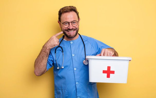 nurse or physician smiling confidently pointing to own broad smile. business and phone concept .first aid kit concept - Φωτογραφία, εικόνα