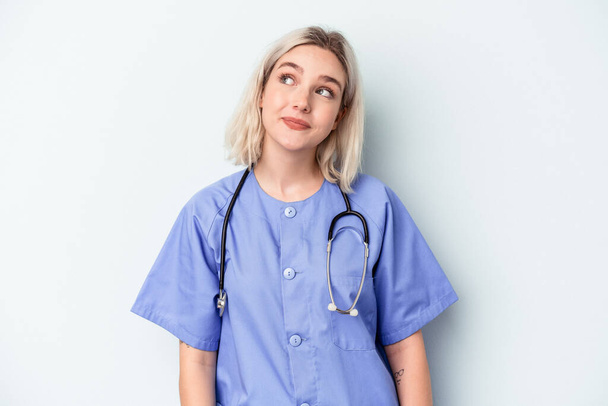 Nuori sairaanhoitaja nainen eristetty sinisellä taustalla haaveilee tavoitteiden ja päämäärien saavuttamisesta - Valokuva, kuva