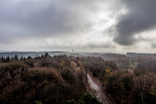 Stormy sky with dark gray clouds on the horizon, thick haze over the trees in the forest seen from the Wilhelmina tower in Vaals, South Limburg in the Netherlands, impressive spectacle of nature - Fotó, kép