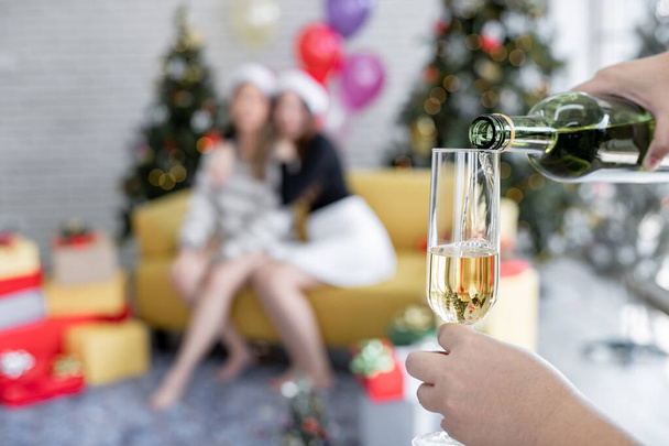 Şarap dolduruyorum, arka planda Noel partisini kutlayan iki kız olarak.. - Fotoğraf, Görsel