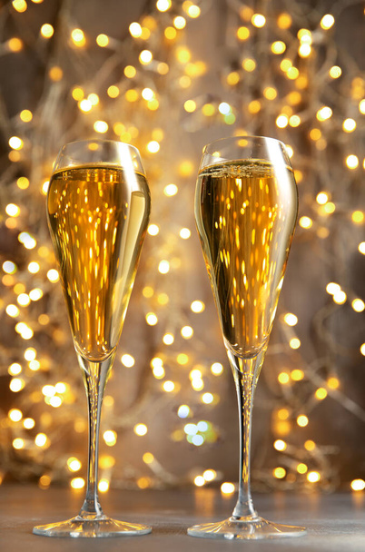 Two glasses of champagne against the background of lights. Selective focus. - 写真・画像