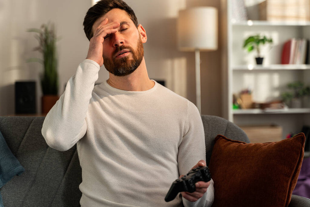Gamer man with joystick lose in the game. Missed the chance to become a champion in tournament. Young guy playing video game online at home  - Foto, afbeelding