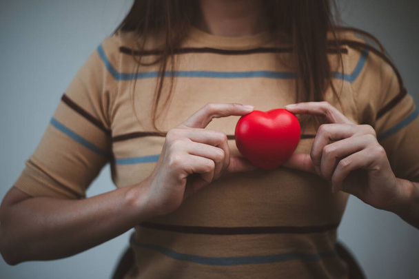 female hands holding red heart, world mental health day and world heart day, Life and health insurance, CSR social responsibility, organ donation, concept of love - Фото, изображение
