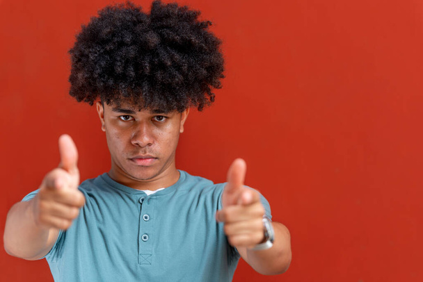 Portrait of serious african american man pointing at camera, isolated on red background, Panama, Central America - Foto, Imagen