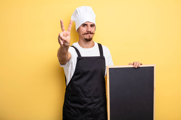chef man smiling and looking friendly, showing number two - 写真・画像