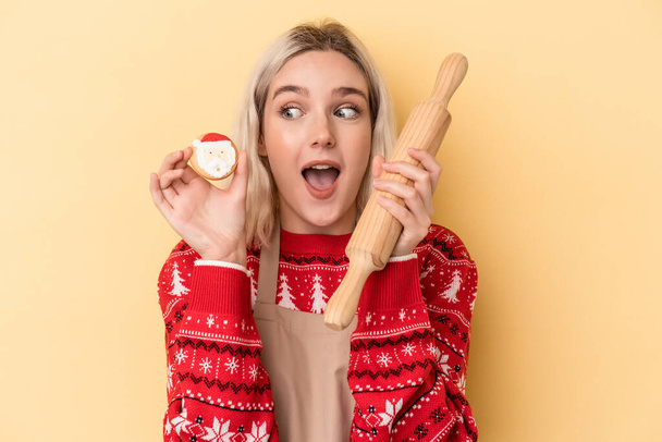 Sarı arka planda izole edilmiş Noel kurabiyeleri tutan beyaz bir kadın. - Fotoğraf, Görsel