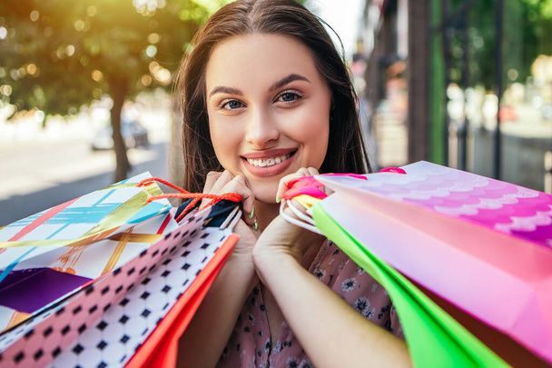 Attractive dark hair lady hold hands many bags shopper woman dressed pink flower pattern dress carrying enjoying new clothes packs things after shopping buyings sales black friday concept - Foto, afbeelding