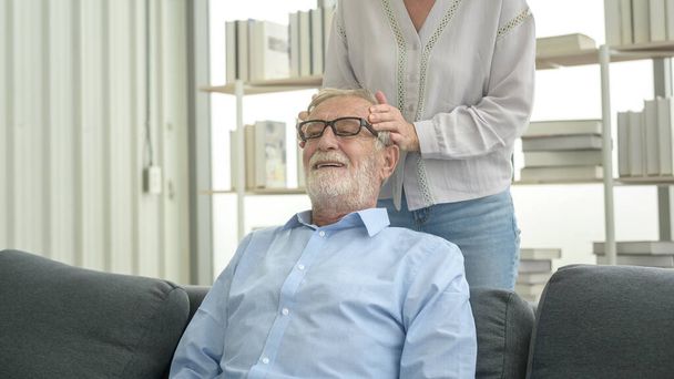Senior caucasian man doing massage for his wife in living room - Фото, зображення