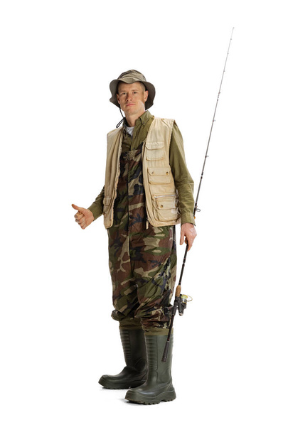 Portrait of young man, professional fisherman with fishing rod, spinning and equipment going to river isolated over white studio background - Foto, Imagen
