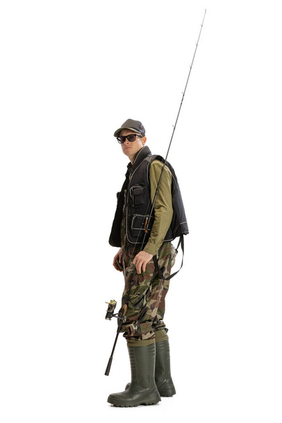 Portrait of young man, professional fisherman with fishing rod, spinning and equipment going to river isolated over white studio background - Foto, afbeelding