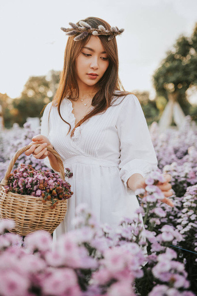 Thai woman with basket with flowers in purple flower field - Foto, Imagem